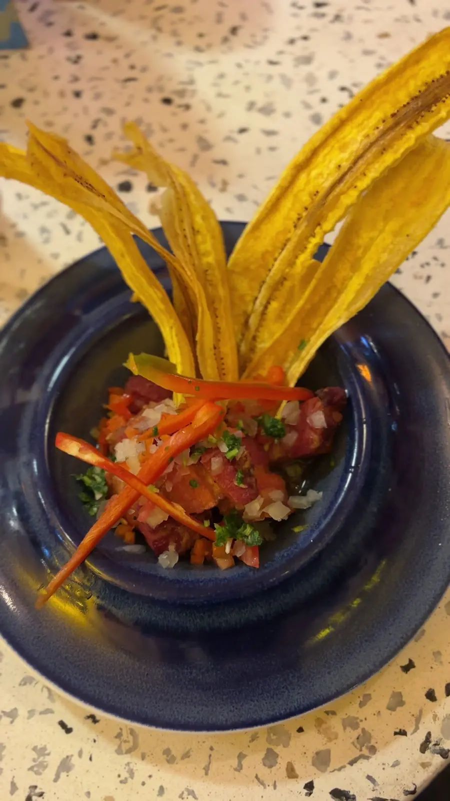Ceviche servido con patacones en un plato azul
