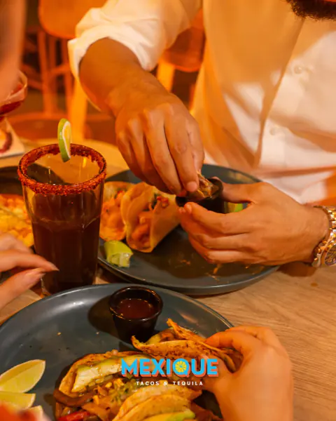 Mesa compartida con tacos, consomé y bebidas
