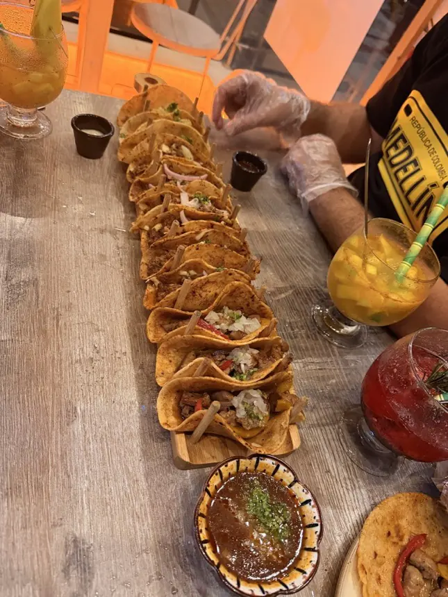 Taquiza larga de tacos de birria con salsas y bebidas